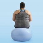 Übergewichtige Frau sitzt auf Gymnastikball, Rückansicht. — Stockfoto