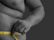 Homem com excesso de peso medindo a cintura com fita métrica . — Fotografia de Stock