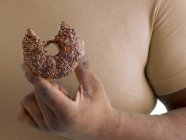 Людина з надмірною вагою тримає пончик з відсутнім укусом . — стокове фото
