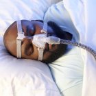 Hombre dormido que usa ventilador para tratar la apnea del sueño . - foto de stock