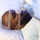 Homem adormecido usando ventilador para tratar a apneia do sono . — Fotografia de Stock