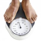 Cropped view of male feet standing on weighing scales. — Stock Photo