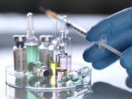 Вчений тримає шприц над різноманітними фармацевтичними флаконами . — стокове фото