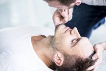Male doctor checking unconscious man breathing. — Stock Photo