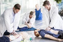 Doctors undertaking cardiopulmonary resuscitation training on dummies. — Stock Photo