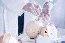 Doctor practicing tracheal intubation on infant training dummy. — Stock Photo