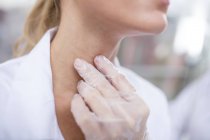Female doctor feeling larynx with gloved hand, close-up. — Stock Photo