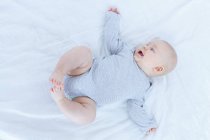 Overhead view of baby boy lying on back in bed. — Stock Photo