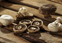 Different types of cultivated edible mushrooms on wooden background. — Stock Photo