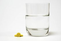 Таблетки і склянка води на білому тлі . — стокове фото