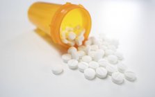 Білі таблетки, що проливаються з відкритого пластикового контейнера . — стокове фото