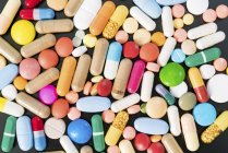 Multicolored pills and capsules on black background. — Stock Photo