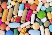 Pilules et capsules multicolores sur fond noir . — Photo de stock
