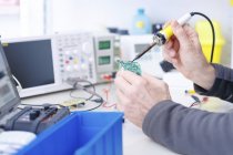 Primo piano del tecnico che ripara il circuito nel laboratorio di elettronica . — Foto stock