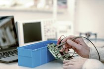 Primer plano del técnico que repara la placa de circuito en el laboratorio de electrónica . - foto de stock