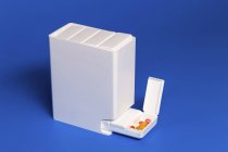 White dispenser with various tablets on blue background. — Stock Photo