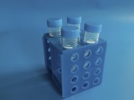 Tubos para teste biológico em rack em fundo azul . — Fotografia de Stock
