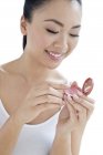 Young Chinese woman applying blusher on white background. — Stock Photo
