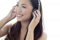 Retrato de una mujer adulta joven escuchando música en auriculares . - foto de stock
