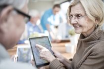 Взрослые люди смотрят на фото на планшете в доме престарелых . — стоковое фото