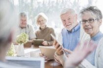 Senior adults talking in care home with tablet computers. — Stock Photo