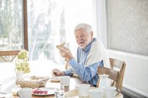 Senior man eating breakfast at table in care home. — Stock Photo