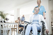 Mujer mayor en silla de ruedas con enfermera en casa de cuidados
. - foto de stock