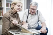 Senior couple looking at photo album together. — Stock Photo
