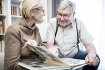 Senior couple looking at each other and smiling with photo album. — Stock Photo