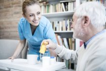 Krankenschwester beugt sich und hält Tablett mit Medikamentenflaschen für Senioren in Pflegeheim. — Stockfoto