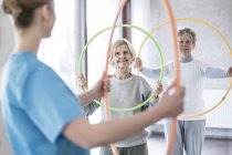 Physiotherapist with senior women holding plastic hoops. — Stock Photo