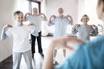 Senior adults exercising in physiotherapy class with nurse. — Stock Photo