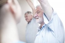 Senior men stretching in exercise class with nurse. — Stock Photo