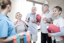 Senior adults holding sport equipment with physiotherapist in exercise class. — Stock Photo