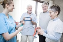 Senior adults holding resistance bands with physiotherapist in exercise class. — Stock Photo