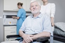 Senior man sitting in wheelchair and looking up in care home. — Stock Photo