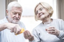 Senior gibt Seniorin mit Glas Wasser Medikamente. — Stockfoto