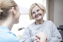 Senior woman smiling at care worker. — Stock Photo
