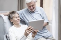 Seniorenpaar im Krankenhauszimmer blickt auf digitales Tablet und lächelt. — Stockfoto