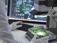 Обрезанный вид инженера с помощью стереомикроскопа для проверки печатной платы . — стоковое фото
