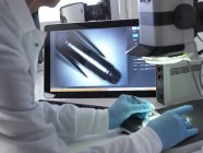 Científico forense usando microscopio estéreo 3d para examinar marcas en la bala . - foto de stock