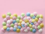 Pastel colored sweets against pink background. — Stock Photo