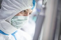 Close-up of lab technician in protective suit and face mask in sterile laboratory. — Stock Photo