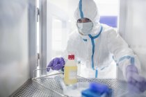 Technician collecting equipment from transfer hatch in sterile laboratory. — Stock Photo