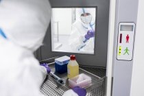 Tecnico che raccoglie attrezzature dal portello di trasferimento in laboratorio sterile . — Foto stock