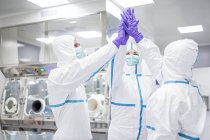 Tecnici di laboratorio che danno il cinque in un laboratorio sterile
. — Foto stock