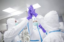 Lab technicians high-fiving in sterile laboratory environment. — Stock Photo