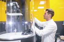Technicien masculin programmant la machine d'électrofilage dans le laboratoire de nanofibre . — Photo de stock