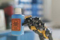Роботизована рука тримає пляшку небезпечної хімічної речовини . — стокове фото