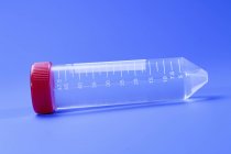 Test tube with red lid on blue background. — Stock Photo